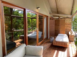 Zimmer mit einer Badewanne und einer Couch auf einer Terrasse in der Unterkunft Summerfields Rose Retreat and Spa in Hazyview