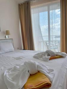 a bedroom with a white bed with a window at Riviera Beach Hotel in Sozopol