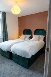 - 2 lits avec des cadres verts dans une chambre dans l'établissement Cozy 2-Bedroom - Cyncoed Area, à Cardiff