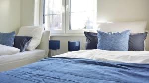 Schlafzimmer mit einem Bett mit blauen und weißen Kissen in der Unterkunft Haus F WHG 1 in Tossens in Butjadingen