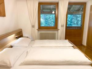 two beds in a room with two windows at Apartments Stroblhof in Ortisei