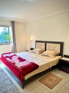 een slaapkamer met een groot bed en een rode deken bij Le Silver in Libreville
