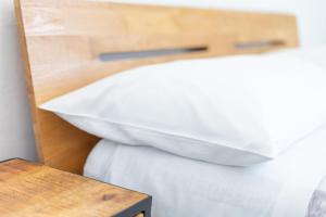1 cama con almohadas blancas junto a una mesa de madera en MaBi en Alghero
