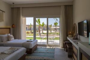 a hotel room with two beds and a sliding glass door at Kynd 01 - Ras El Hikma, GAIA Compound in Marsa Matruh