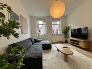 a living room with a black couch and a tv at FLATLIGHT - Stylish apartment - Kitchen - Parking - Netflix in Hildesheim