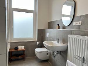 uma casa de banho com um lavatório, um WC e um espelho. em FLATLIGHT - Stylish apartment - Kitchen - Parking - Netflix em Hildesheim