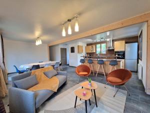 a living room with a couch and chairs and a kitchen at Gite au Doubs Chalet in Ornans