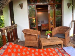 a porch with wicker chairs and a table with a table at Lala Land Lodge in Kizimkazi