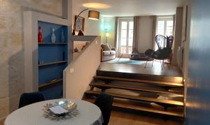 Una sala de estar y una escalera con mesa y sillas. en Burdigala Homes - Appart du Jardin Public, en Burdeos