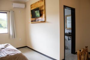 Habitación con cama, espejo y lavabo. en Hotel Águas Lindas, en Itamonte
