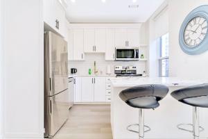 una cocina con armarios blancos y un reloj grande en la pared en 2BR Apartment in James Street, en Hamilton