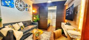sala de estar con sofá y TV en Stylish&Comfort Unit in Air Makati by Luca's Cove en Manila