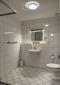 a white tiled bathroom with a sink and a toilet at Hotel Brauhaus Bückeburg in Bückeburg