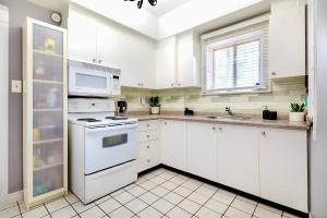 een witte keuken met witte apparatuur en een raam bij Charming Corktown Home with a Backyard in Hamilton