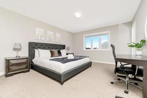 een slaapkamer met een bed en een bureau bij Serene 3BR Home - Sun Deck - Near Victoria Park in Kitchener