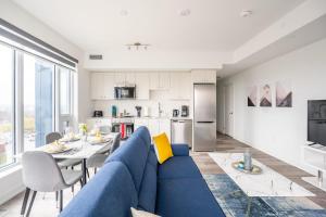 a living room with a blue couch and a kitchen at 1BR Modern Condo - King Bed and Stunning City View in Kitchener