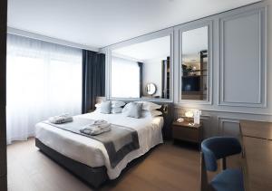 a bedroom with a large white bed with windows at Grand Hotel Terme Sirmione in Sirmione