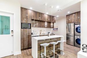 una cocina con armarios de madera, fregadero y taburetes en Modern Pet-friendly Chinatown Apartment en Toronto