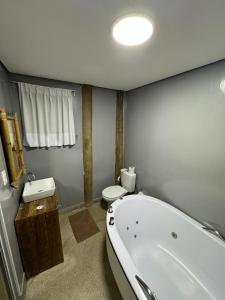 a bathroom with a tub and a toilet and a sink at Pousada Pé na Areia in Abraão
