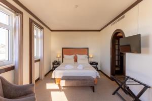 a bedroom with a bed and a flat screen tv at Hotel Inglaterra - Charme & Boutique in Estoril +37 photos