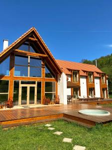 a large house with a wooden deck in front of it at Scrind 11 - Madleine Chalet in Cluj-Napoca