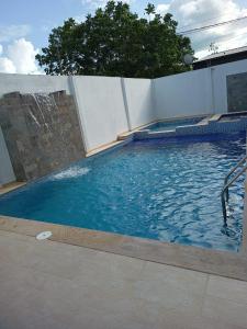 uma piscina com água azul ao lado de uma parede em Vivienda Turística el Refugio em Villavicencio