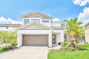 a white house with a palm tree and a garage at Modern 6BR Home - Pool BBQ Hot Tub - Near Disney in Kissimmee