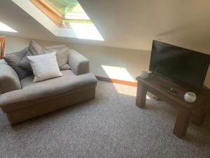 a living room with a couch and a flat screen tv at Mandarin Cottage- quirky upside down retreat - Norfolk in Mileham