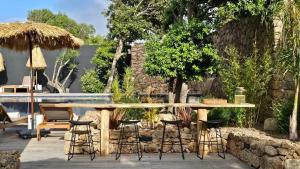 une terrasse avec une table, des chaises et une piscine dans l'établissement Hôtel Les Suites Du Maquis, à Bonifacio