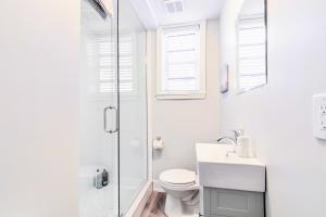a white bathroom with a toilet and a shower at Central Corktown Apartment for City Explorers in Hamilton