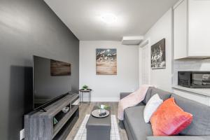 a living room with a couch and a tv at 1BR Basement Condo - James Street in Hamilton