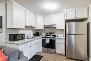 a kitchen with white cabinets and a stainless steel refrigerator at 1BR Basement Condo - James Street in Hamilton