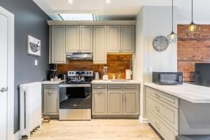 una cocina con armarios blancos y un reloj en la pared en Hamilton's Best Neighbourhood 1BR Apartment, en Hamilton
