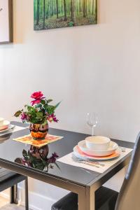 una mesa con platos y un jarrón con flores. en Hamilton's Best Neighbourhood 1BR Apartment, en Hamilton