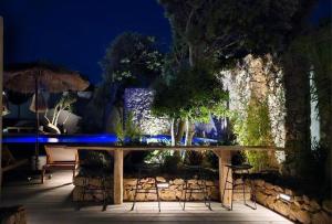 a patio with a table with chairs and trees at night at Hôtel Les Suites Du Maquis in Bonifacio