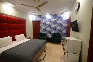 a bedroom with a bed and two green chairs at SEAVIEW COTTAGE in Karachi