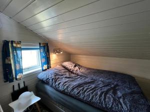 Visit Leif at Senja في Gibostad: سرير في غرفة صغيرة مع نافذة
