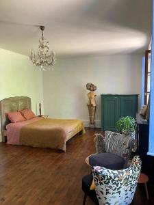 een slaapkamer met een bed, een stoel en een kroonluchter bij Casa Bella in Charroux-dʼAllier
