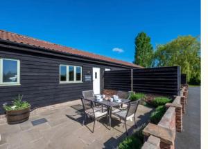 un patio avec une table et des chaises devant une maison dans l'établissement Folkards Farm Holiday Cottages with hot tubs, à Norwich