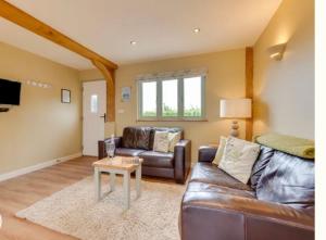 un salon avec un canapé en cuir et une table dans l'établissement Folkards Farm Holiday Cottages with hot tubs, à Norwich