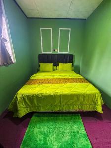 ein Bett in einem grünen Zimmer mit einer gelben Decke in der Unterkunft Green Savanah Homestay Syariah in Diyeng