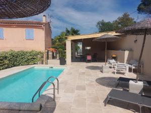 a swimming pool with chairs and umbrellas next to a house at Villa CALLY, chez MARIUS in Vidauban