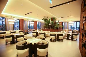a restaurant with white tables and chairs and windows at Regina Palm Resort in Orikum