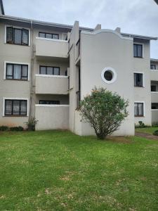 a large white building with a tree in front of it at Newly Renovated 2 bed Apartment - Kingston Estate in Ballito