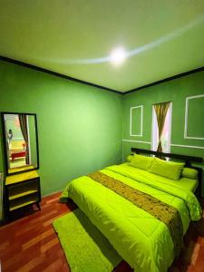 ein grünes Schlafzimmer mit einem Bett und einem Spiegel in der Unterkunft Green Savanah Homestay Syariah in Diyeng