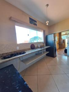 a kitchen with a counter and a window and a refrigerator at Hospedagem Recanto dos Anjos in Arraial do Cabo