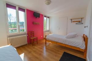 sypialnia z łóżkiem i różową ścianą w obiekcie Hôtel La Barguelonne w mieście Montcuq