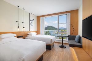 ein Hotelzimmer mit zwei Betten und einem Flachbildfernseher in der Unterkunft Fairfield by Marriott Hangzhou Qiandao Lake in Thousand Island Lake