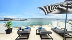 une terrasse avec des chaises et un parasol et l'océan dans l'établissement Blue Marina Suites - Boutique Apartments, à Arrecife