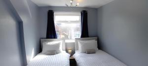 2 camas en una habitación pequeña con ventana en Home and Away Guesthouse, en Bridlington